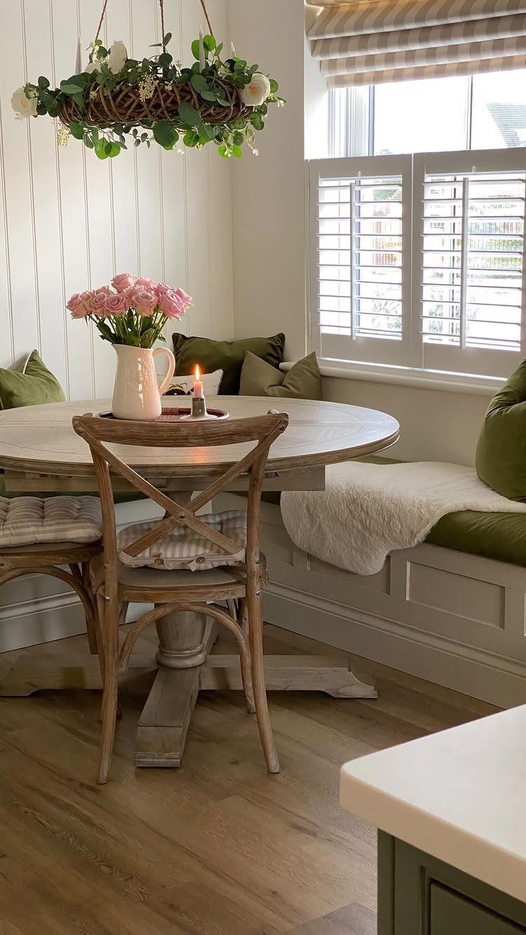 Round wooden dining table with a built-in L-shaped banquette seat and green cushions.