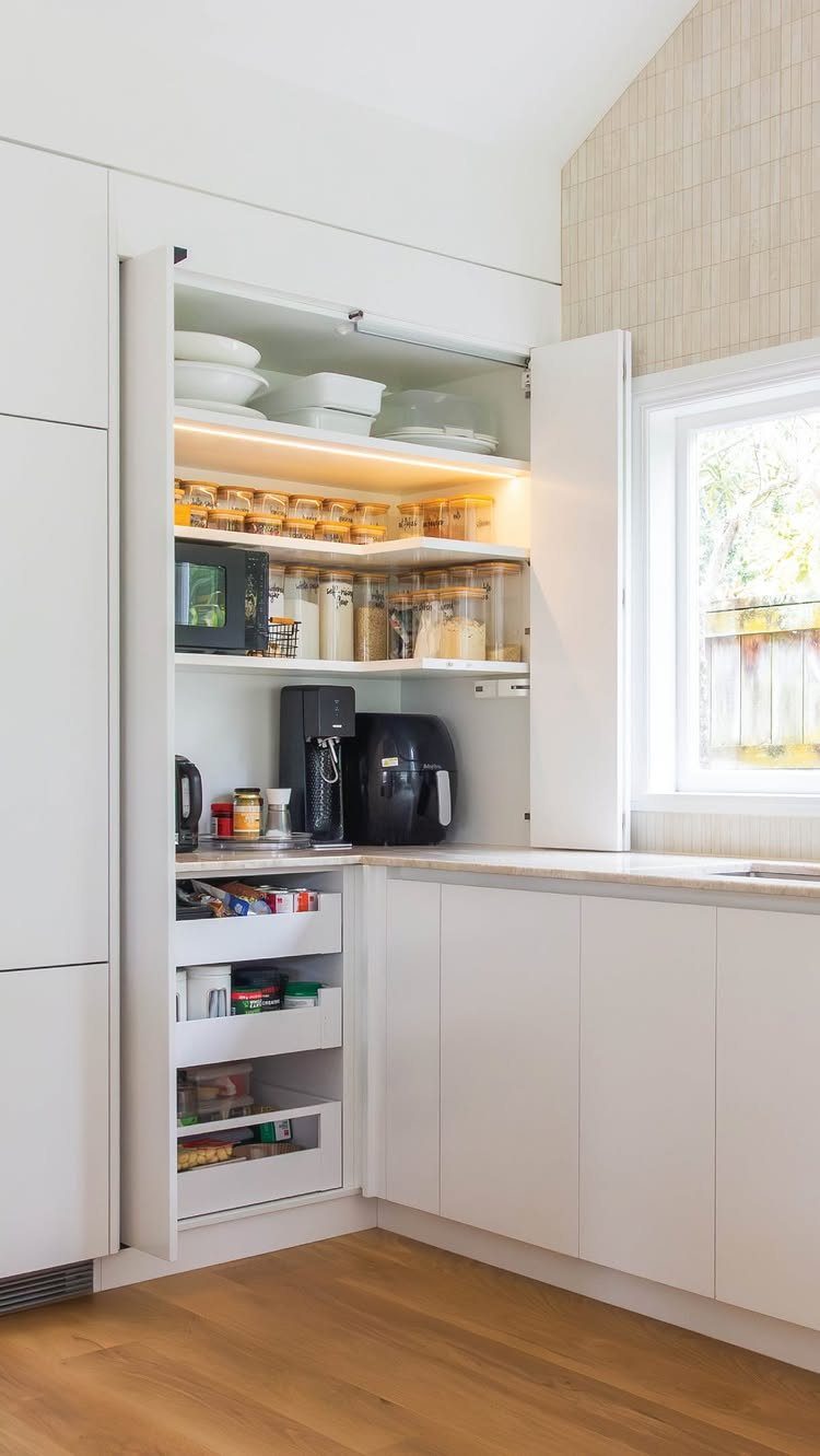 Built-in white kitchen pantry with coffee maker, microwave, and organized pull-out storage drawers.