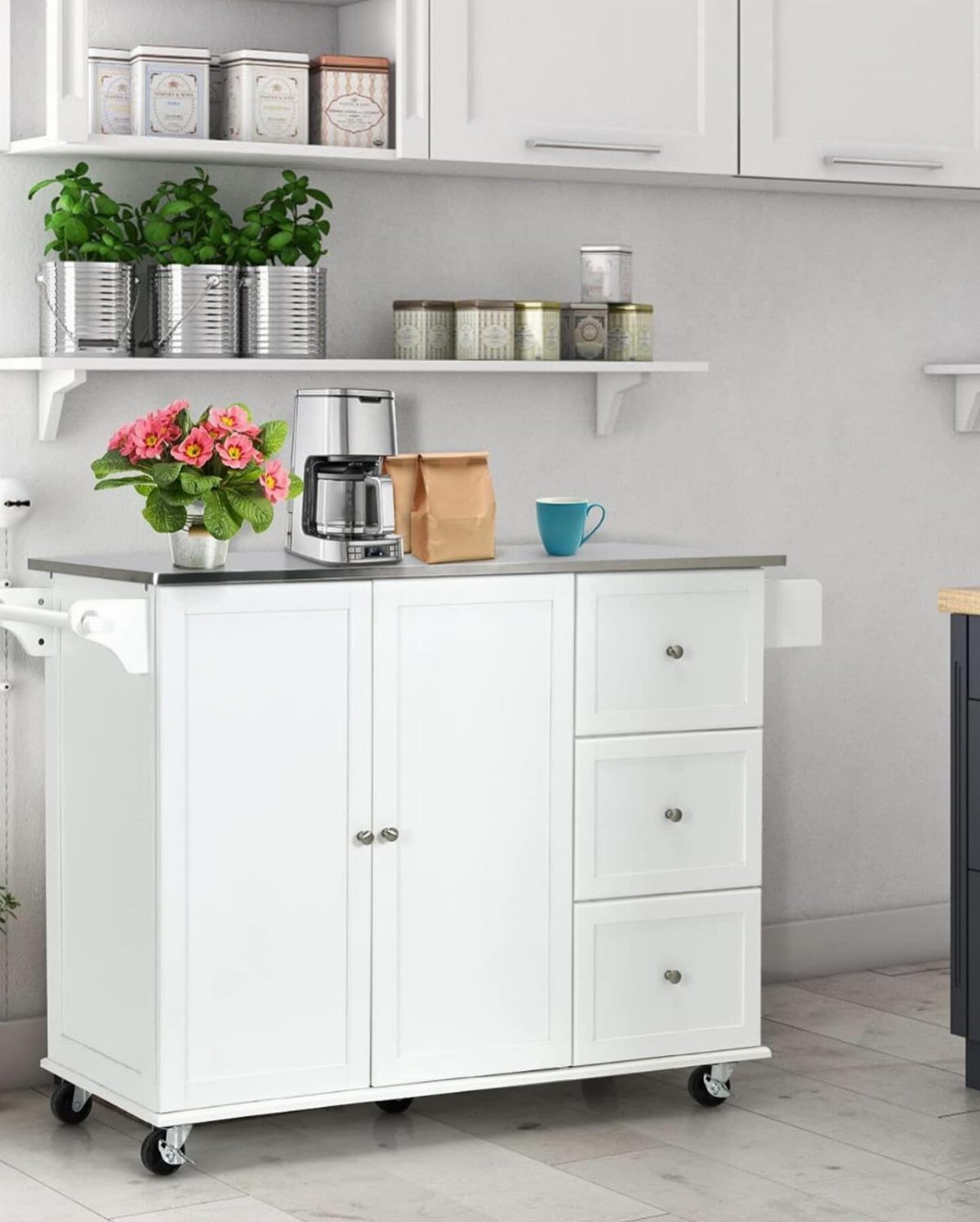 White movable kitchen island with grey countertop, coffee maker, and pink flowers.