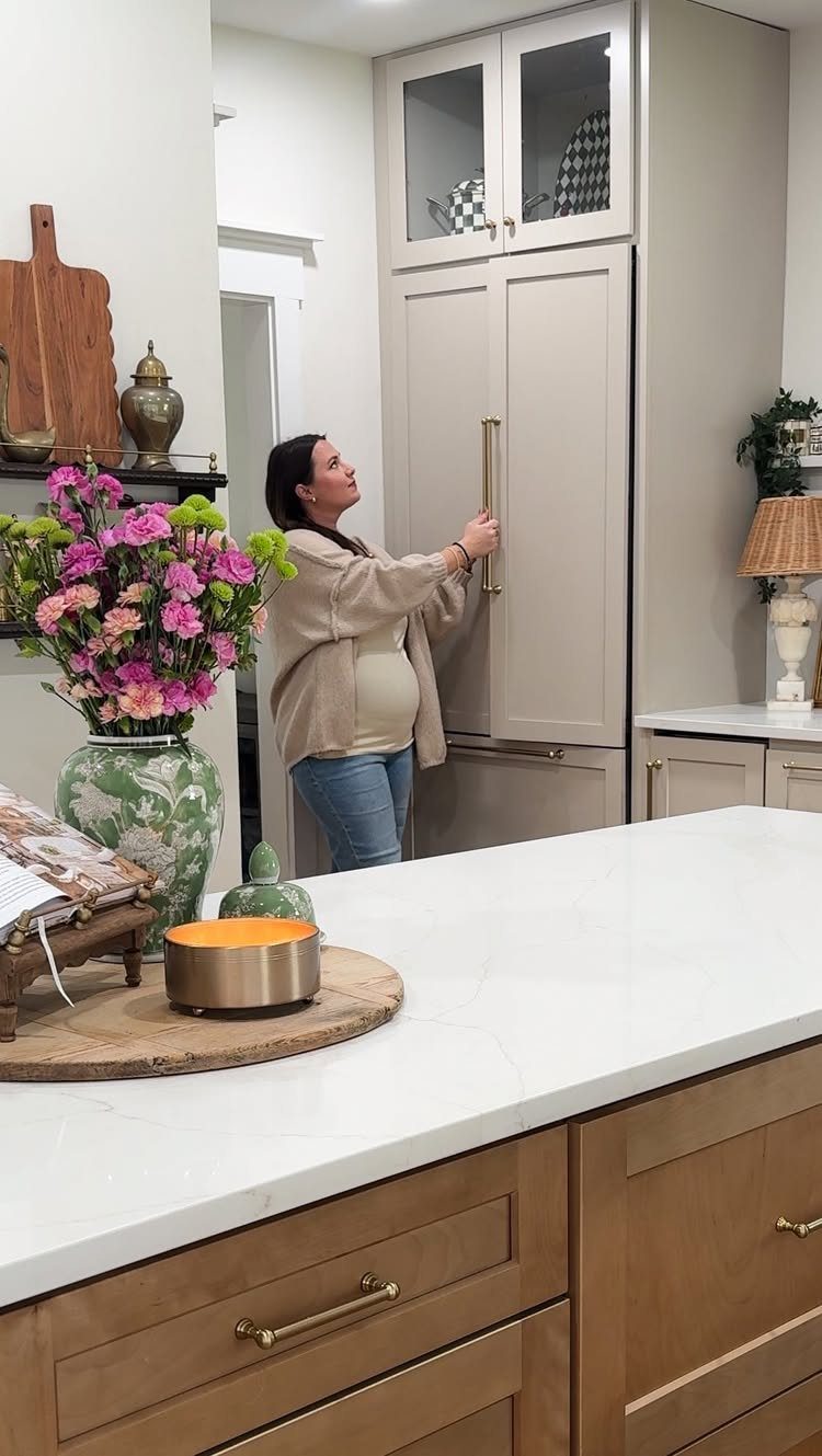 Woman opening a beige panel-ready refrigerator that matches the kitchen cabinetry.