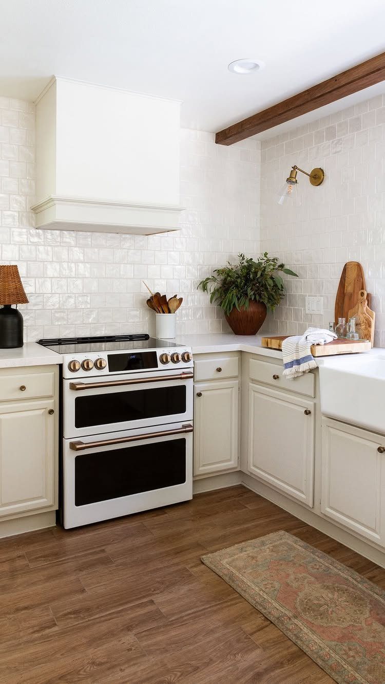 White kitchen with lower cabinets and no upper cabinets against a tiled wall.