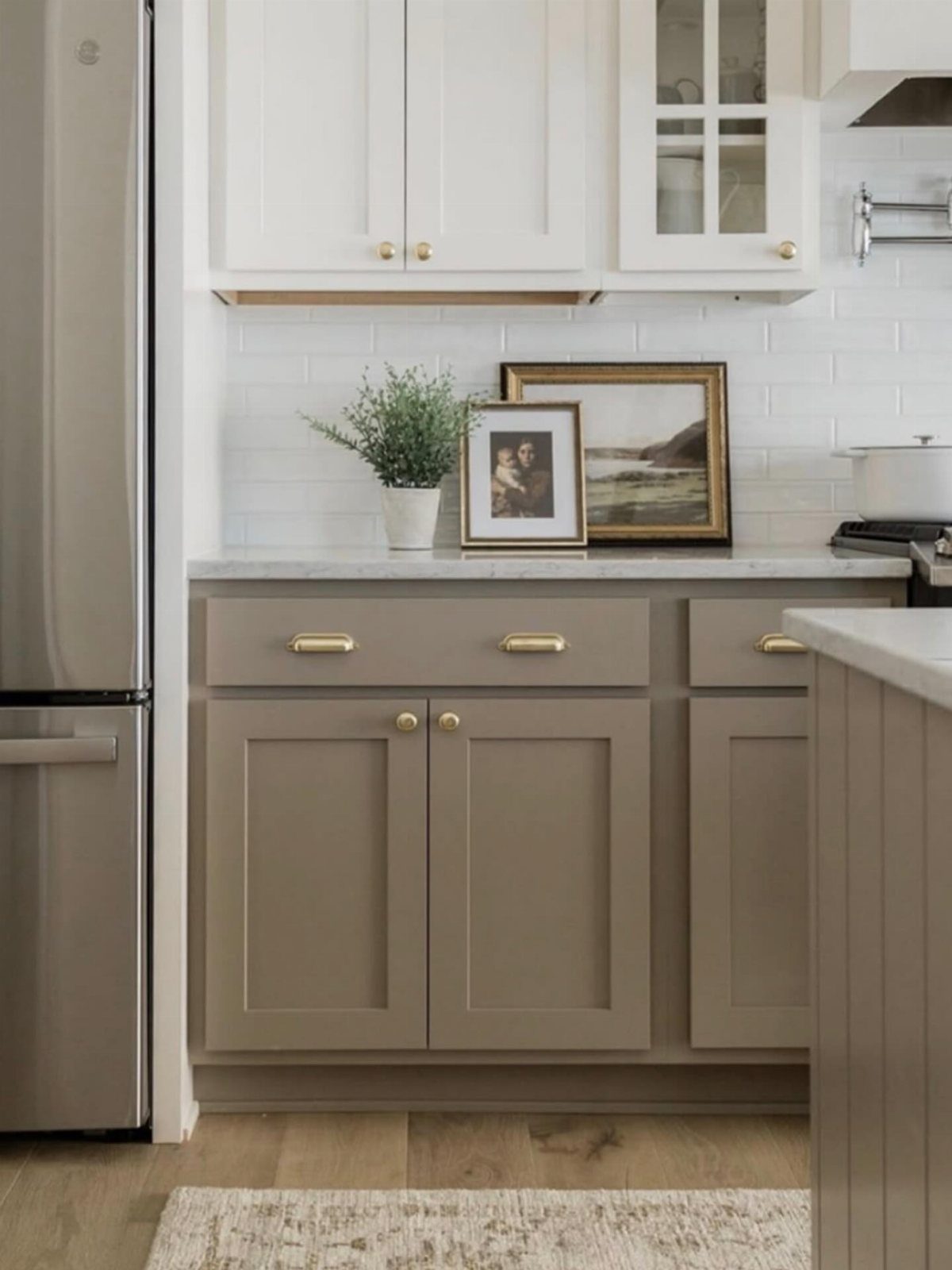 White upper and taupe lower shaker cabinets with gold hardware in a kitchen.