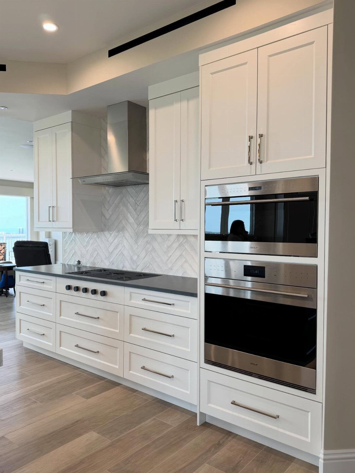 Double stainless steel wall ovens built into white shaker cabinets in a modern kitchen.