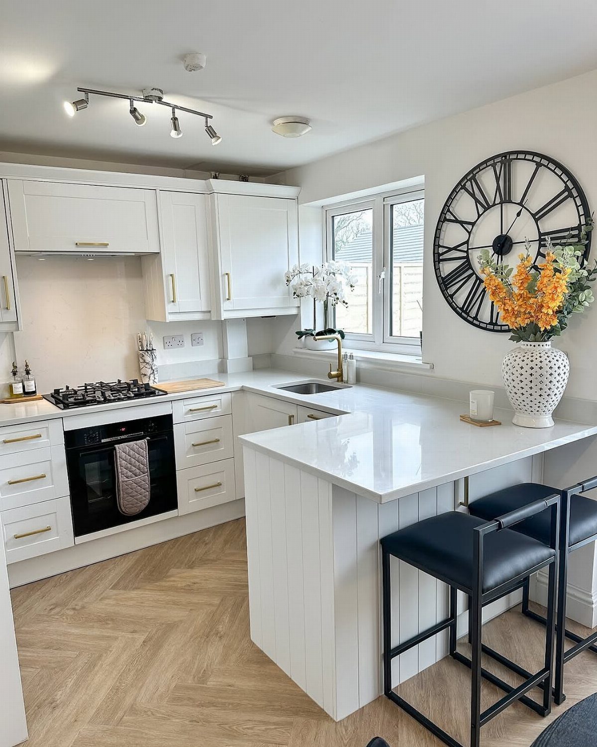 White shaker cabinets with gold hardware in a bright kitchen with a peninsula.