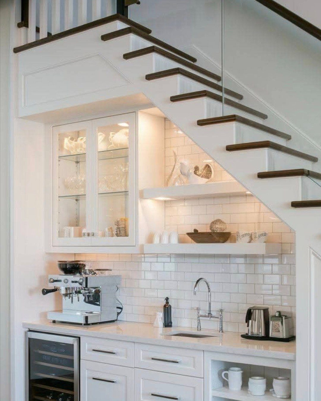 Coffee station with espresso machine and sink built into the space under a staircase.