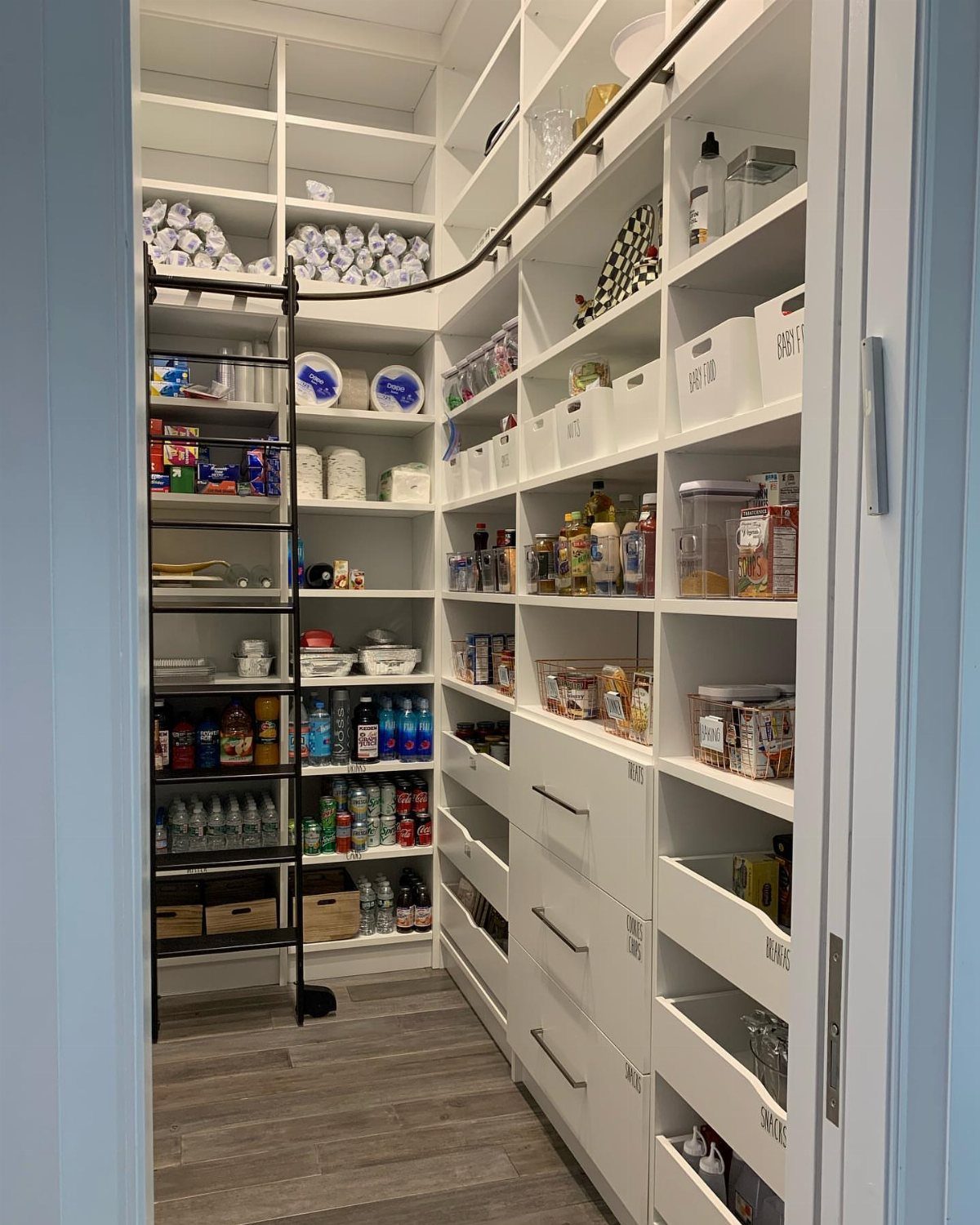 White L-shaped pantry shelving with built-in drawers and a black rolling storage rack.