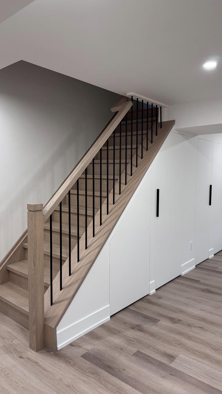 Wooden staircase with white built-in storage cabinets installed underneath the stairs.