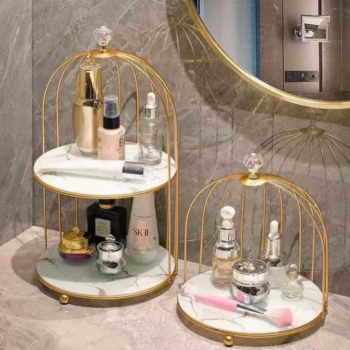 Gold metal cage shelves with marble tiers holding skincare products on a bathroom counter.