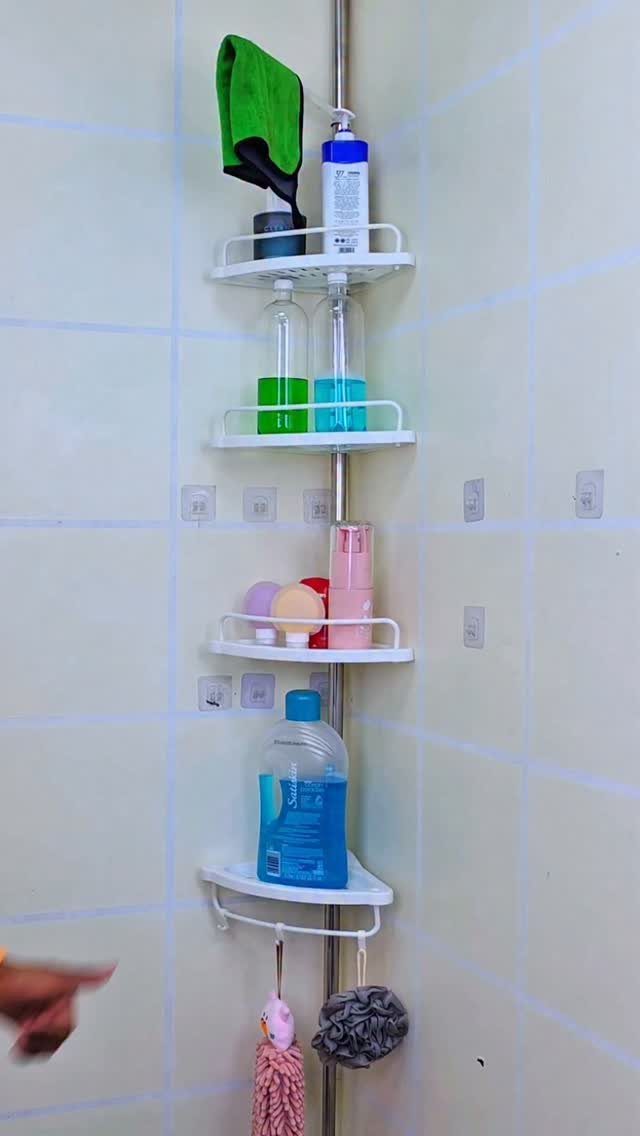 White corner shower caddy with four shelves holding toiletries against tiled walls