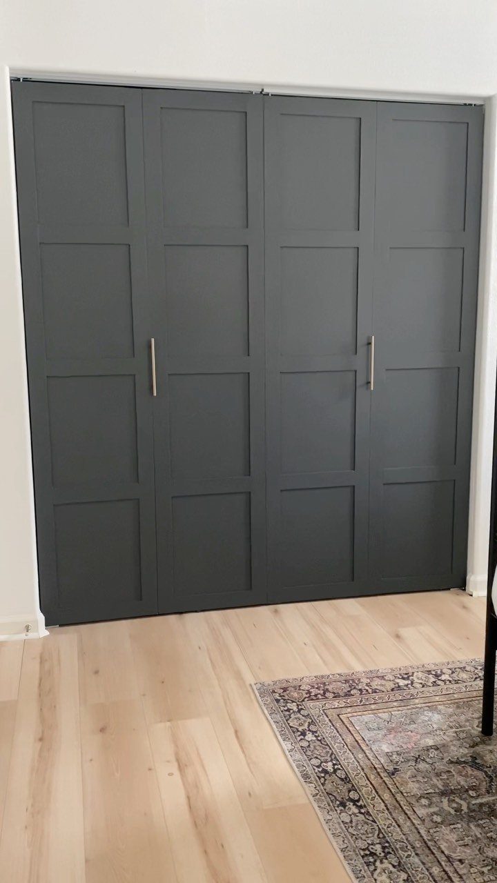 Dark grey paneled bifold closet doors with slim vertical metal handles on wood floors