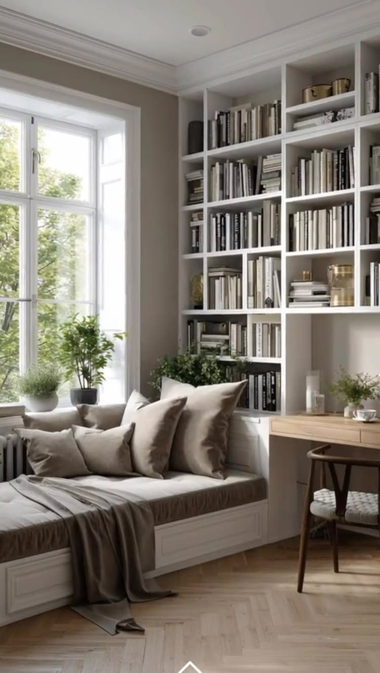 Built-in desk and shelving unit next to a cozy window seat with beige pillows.