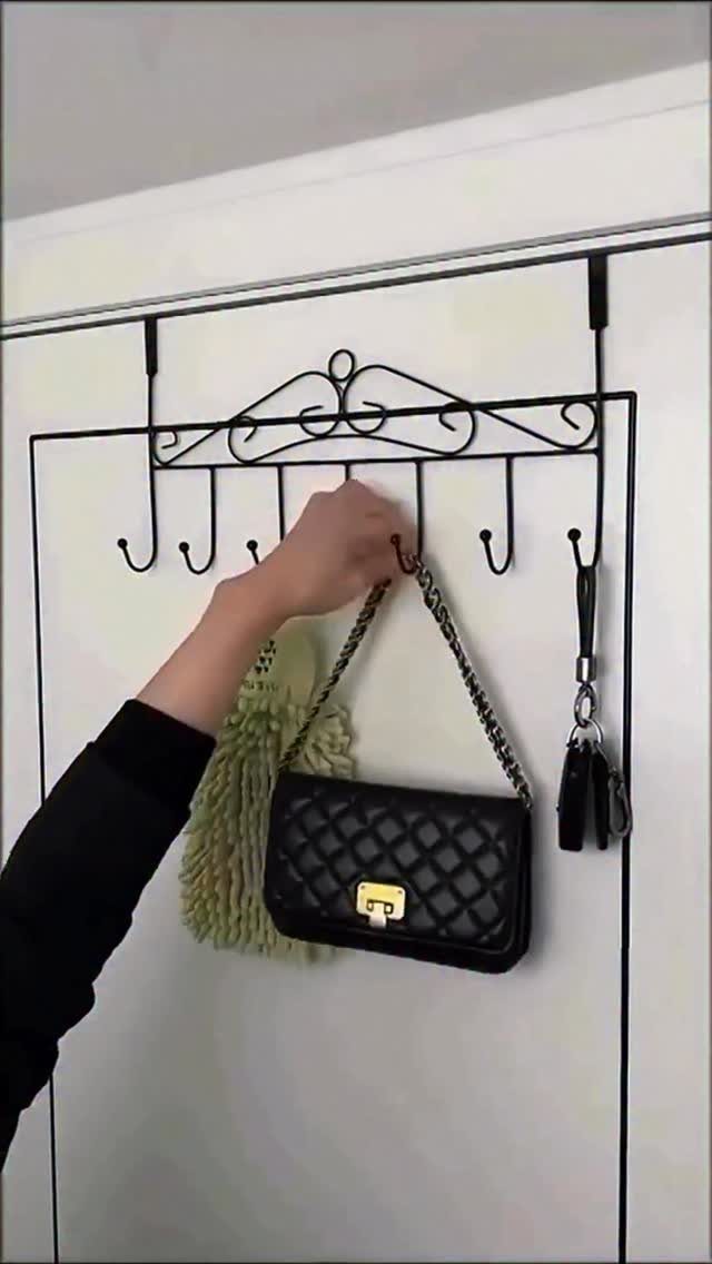 Black metal over-the-door hook rack holding a quilted handbag and fuzzy accessory.