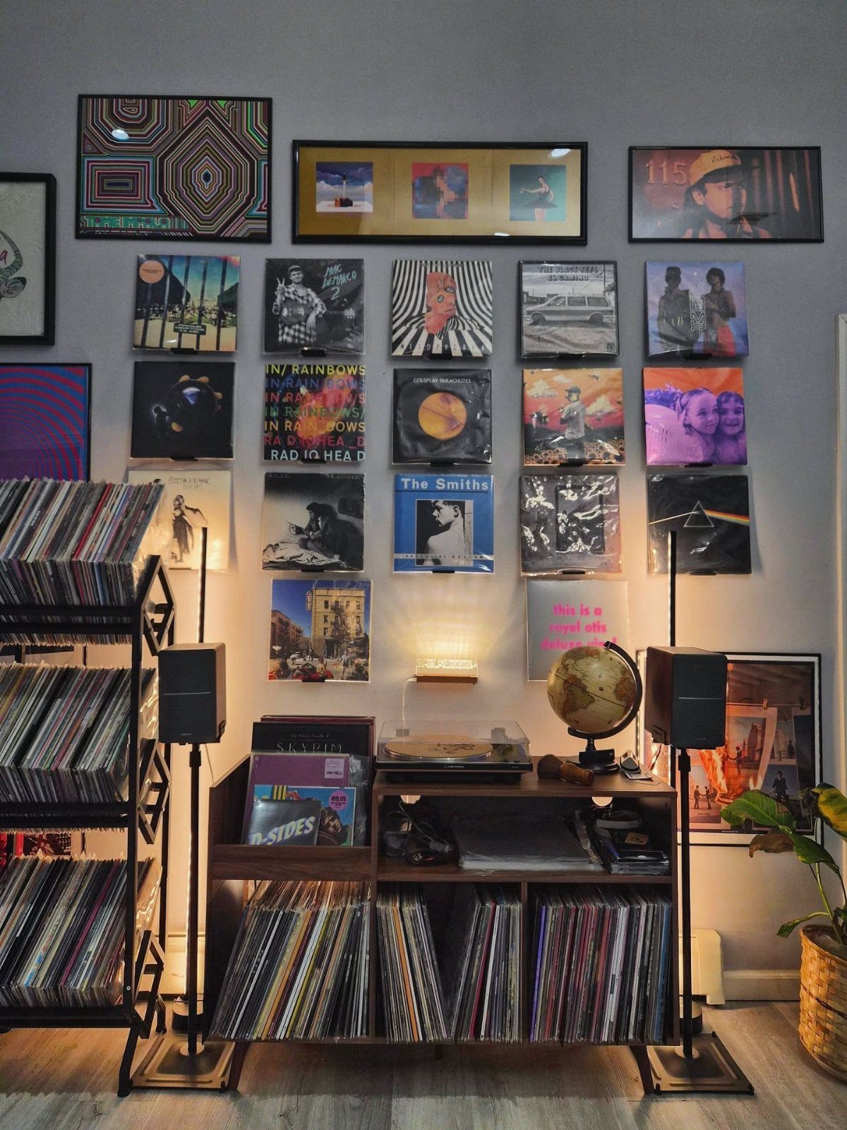 Record player on a wooden shelf surrounded by vinyl records and wall art.