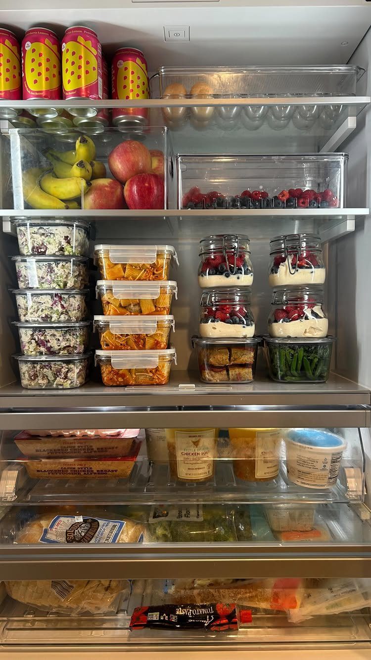 Organized refrigerator interior with meal prep containers, clear bins, and layered fruit parfaits.