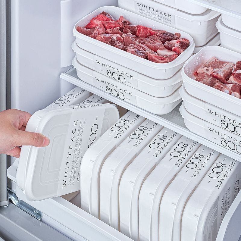 White plastic food storage containers filled with raw meat inside a white refrigerator.