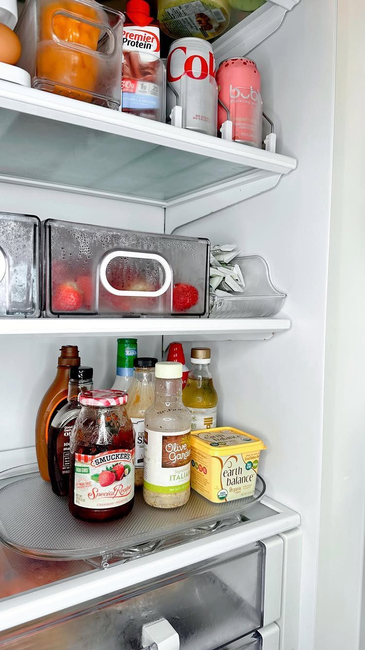 Rotating turntable in a refrigerator holding various condiment bottles and a butter container.