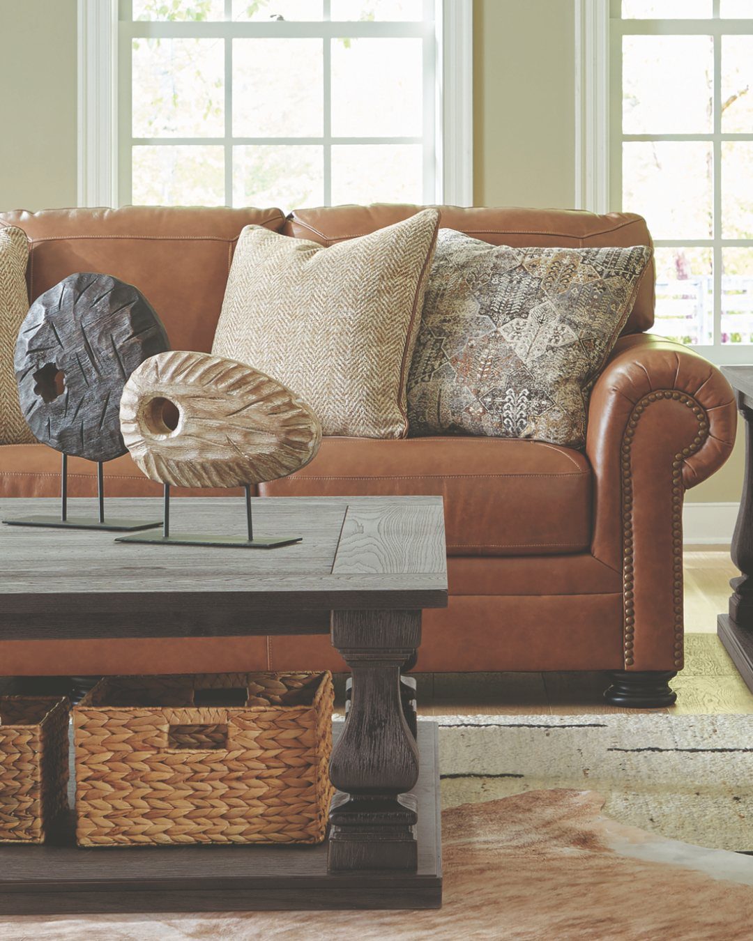 Caramel leather sofa with nailhead trim and decorative pillows in a bright living room