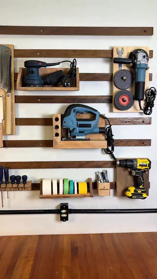 Power tools organized on a wall using a brown wooden French cleat system.