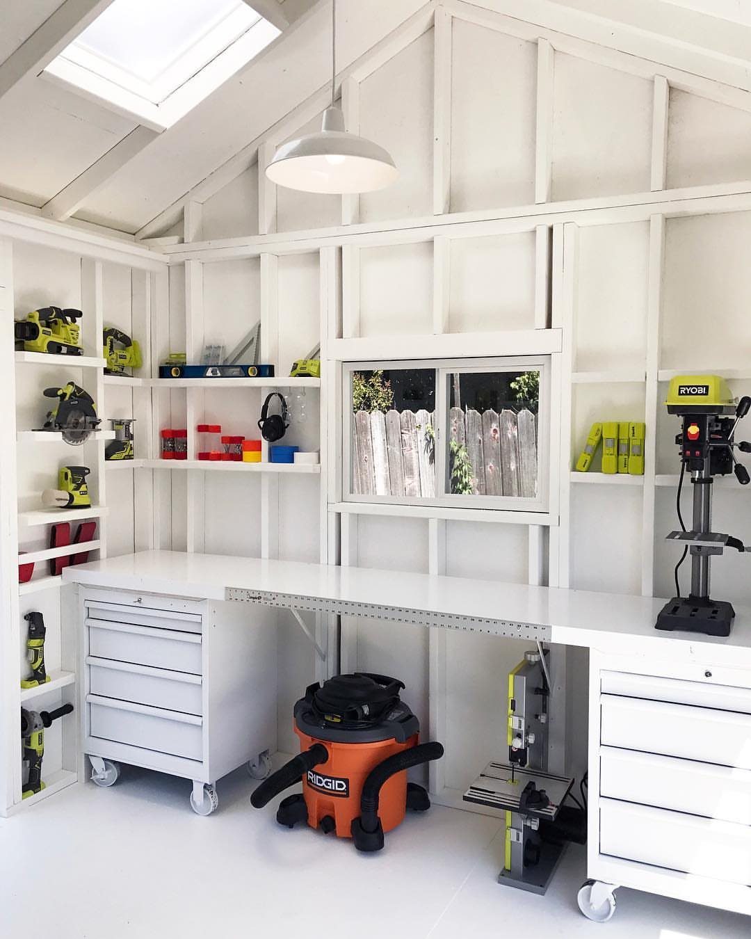 White workshop with organized workbench, shelving, and power tools in a bright room.