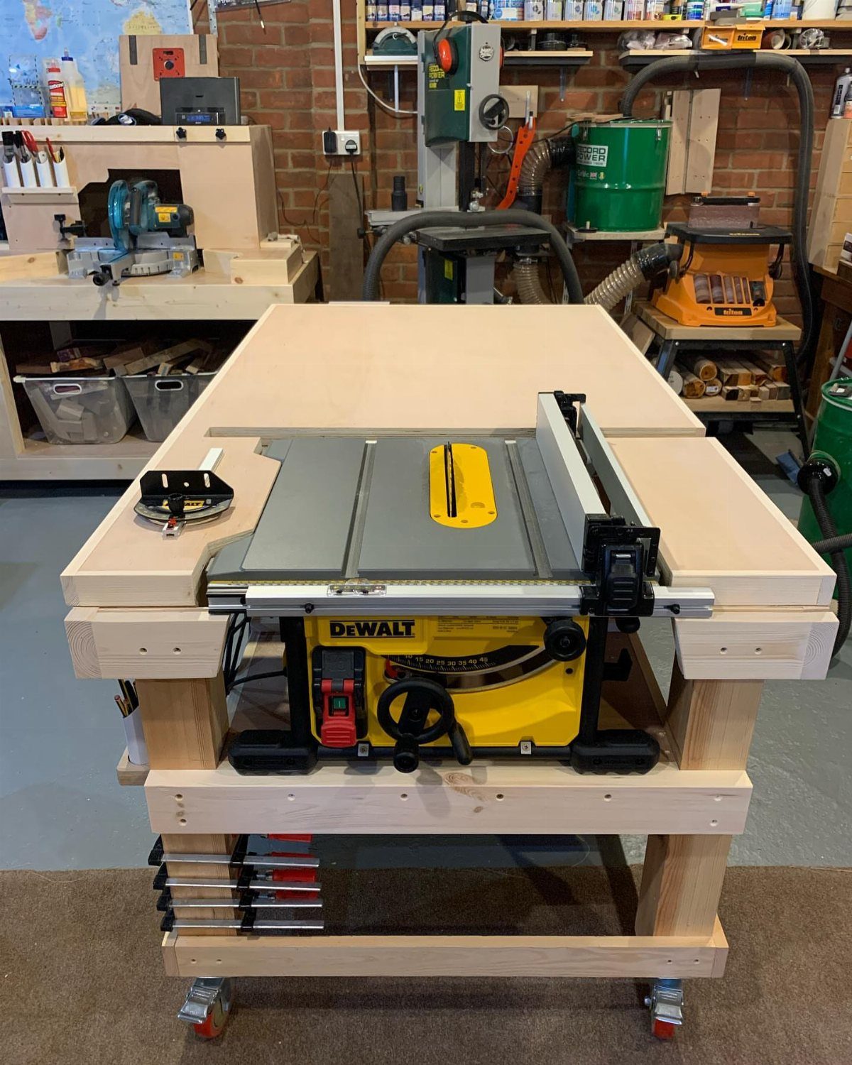Table saw integrated into a custom wooden workbench station on wheels in a workshop.