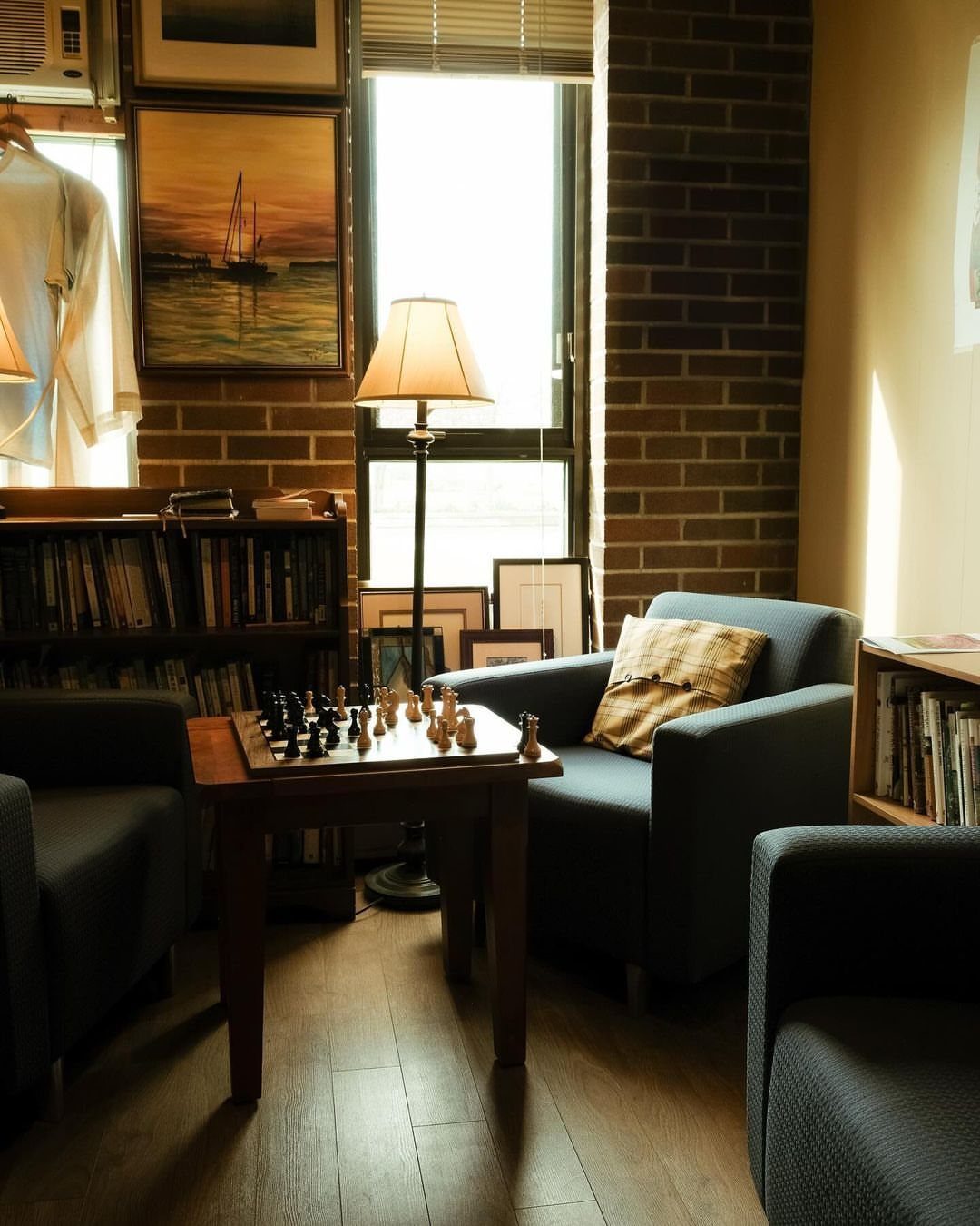 Wooden chess table with pieces set up in a cozy living room with armchairs.