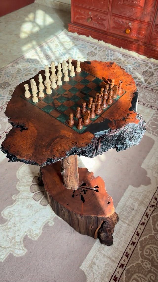 Live-edge wooden chess table with pieces on a patterned rug in a living room.
