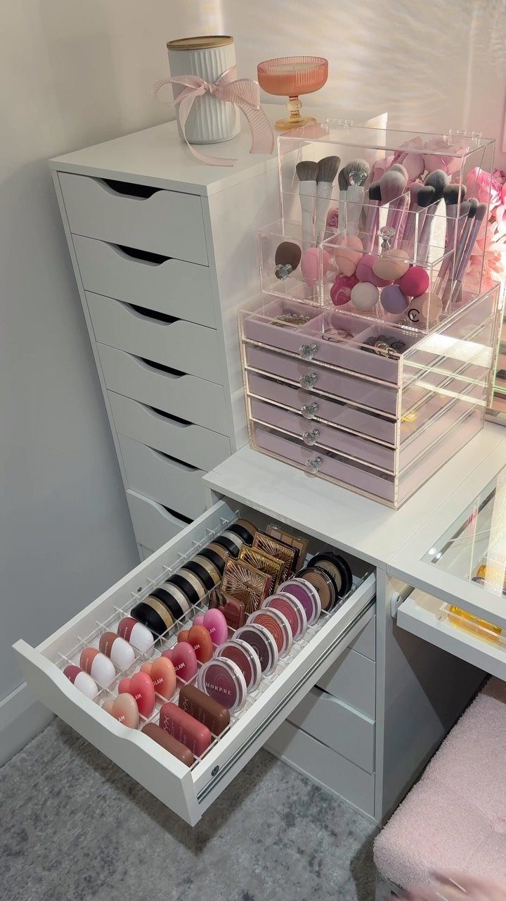 Acrylic accessory holders and makeup organizers on a white vanity with open drawers.
