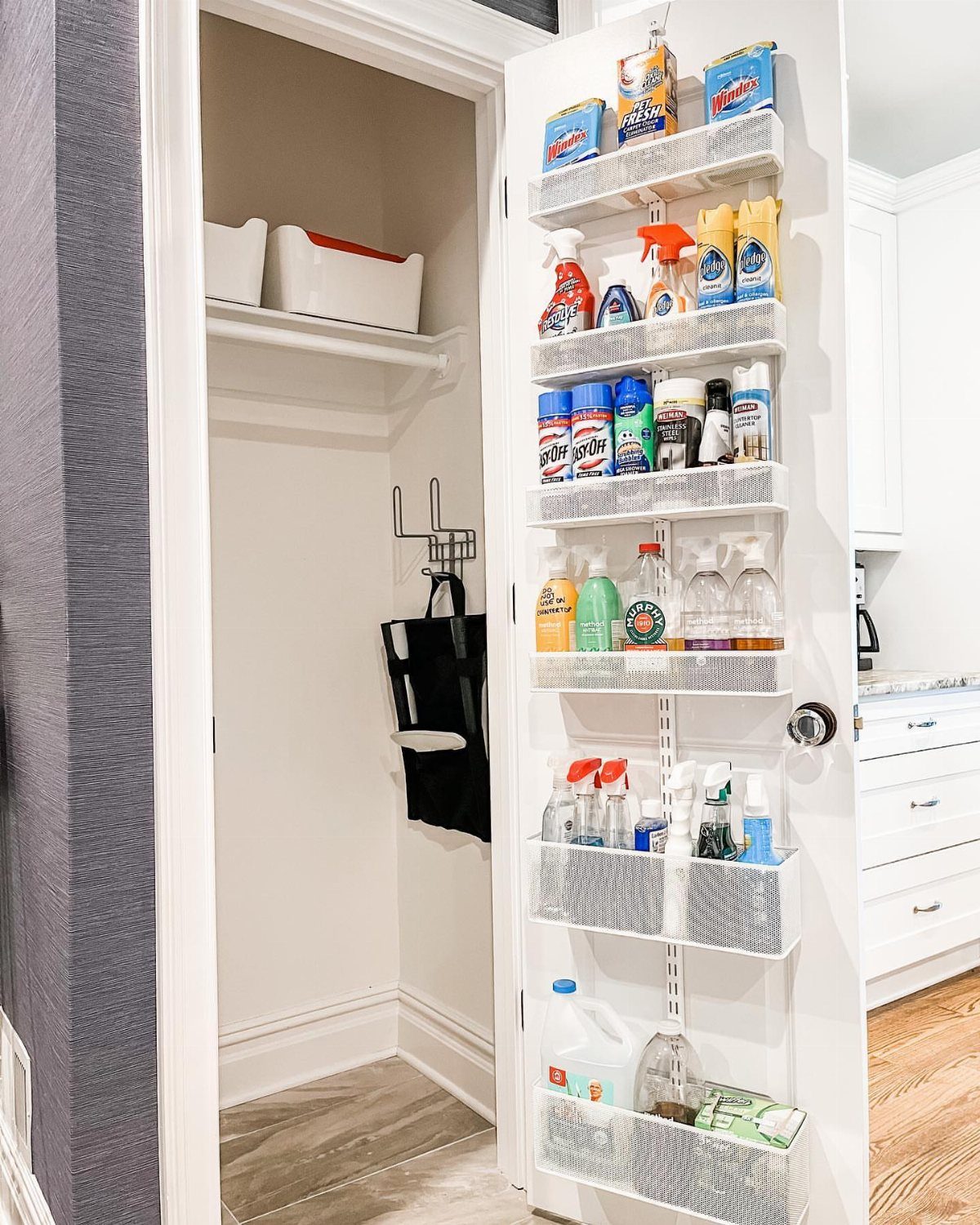 White over-the-door hanging organizer filled with cleaning supplies on a white closet door.