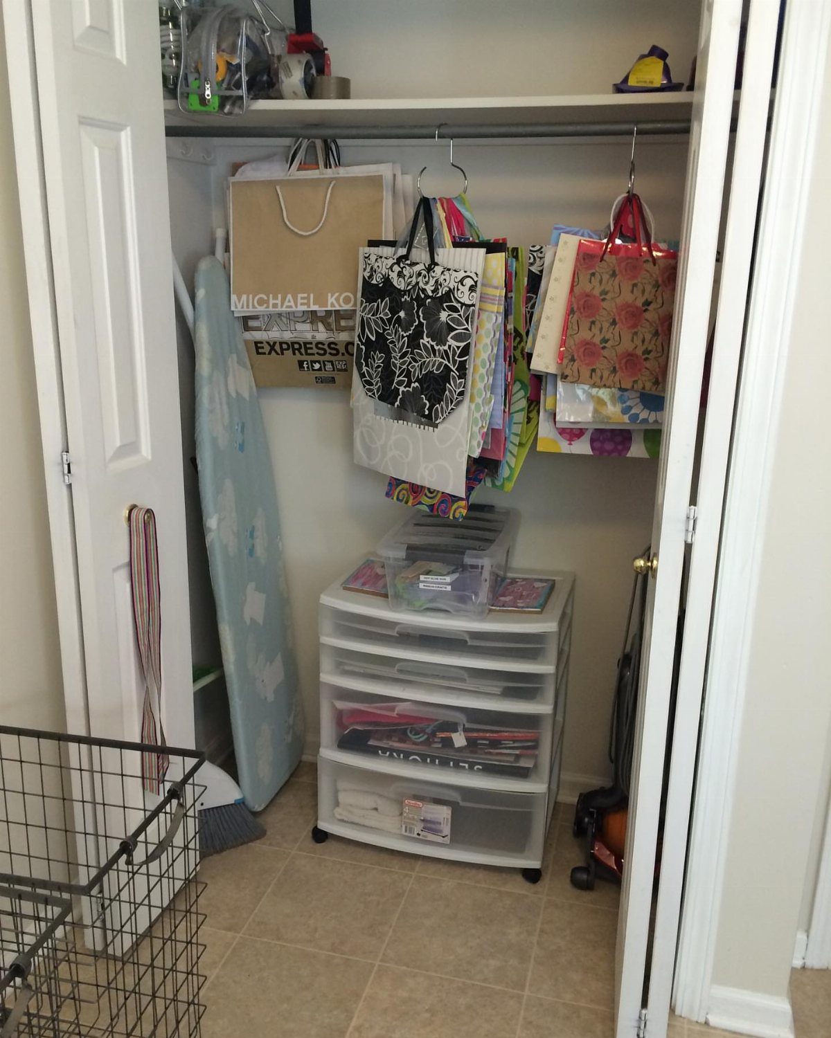 White closet with plastic drawers and colorful shopping bags used for storage.