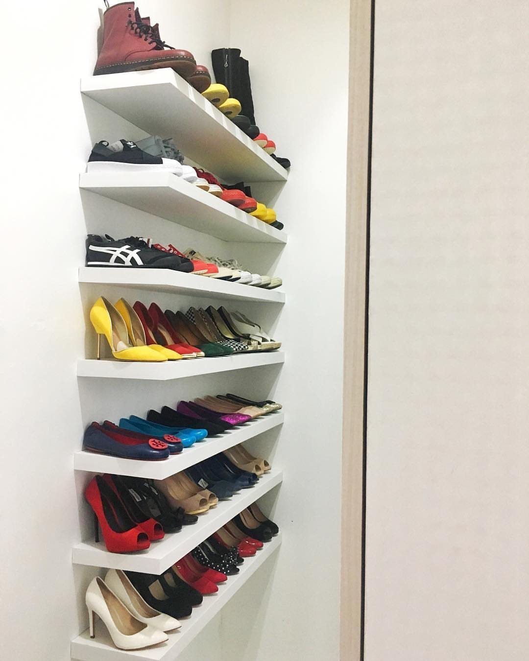 White floating shelves holding a variety of organized shoes and high heels.