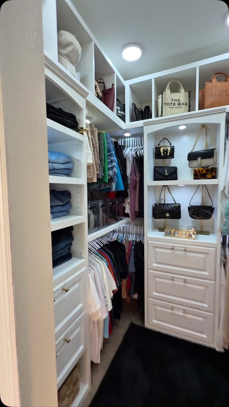 White built-in closet organizer with shelves, drawers, and hanging clothes in a small space.