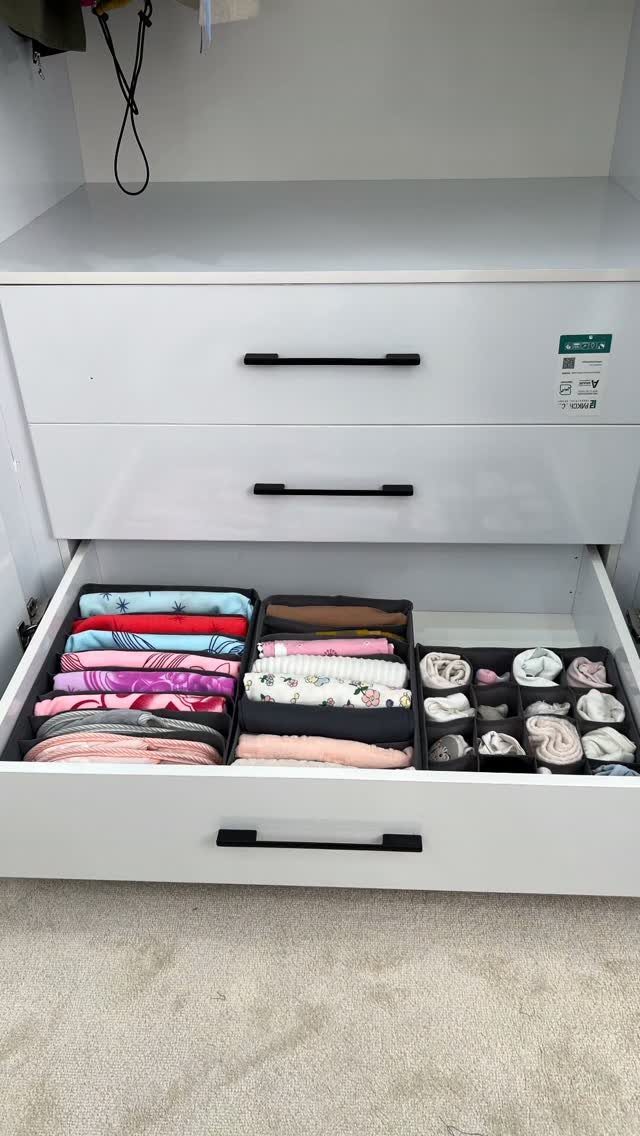 Folded colorful clothes and rolled socks organized inside a white dresser drawer.