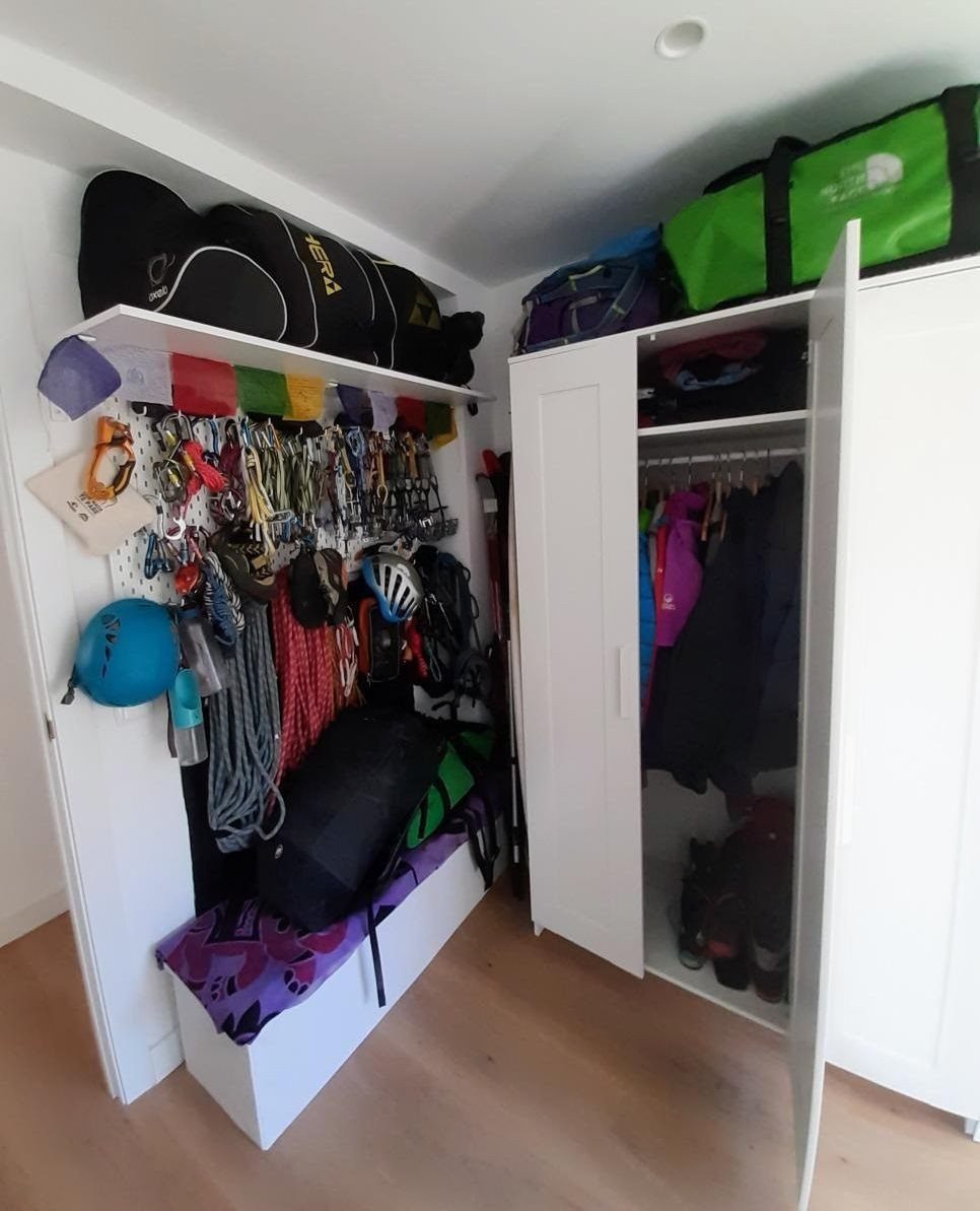 White closet with organized climbing gear, ropes, and clothing in a compact space.