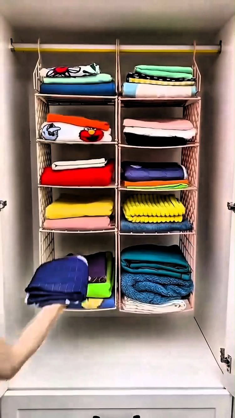 Hanging fabric organizer with folded colorful clothes suspended from a white closet rod.
