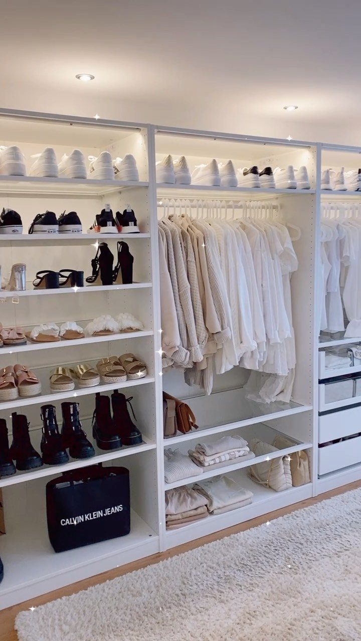 Bright white walk-in closet with organized white clothing, shoes, and built-in shelving.