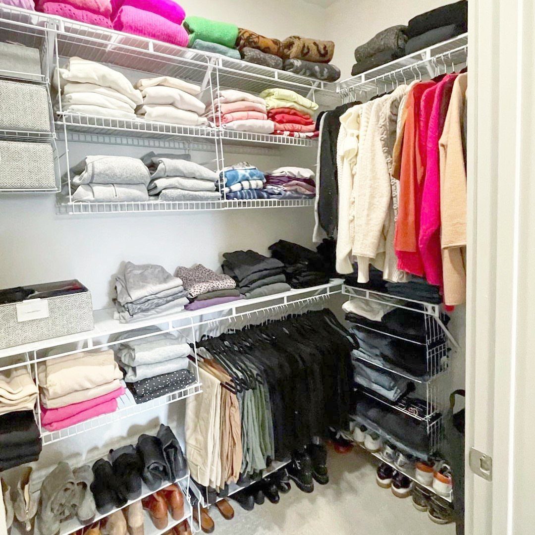 Organized walk-in closet with white wire shelving, folded clothes, and hanging garments.