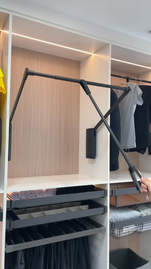Modern white closet with a black pull-down rod and integrated storage drawers.