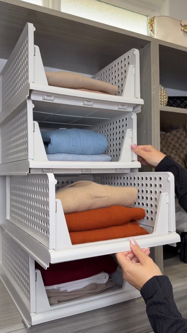 White plastic pull-out closet drawers holding folded colorful clothes in a grey shelf.