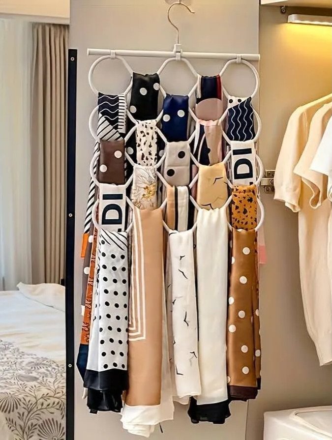 White multi-ring scarf hanger organizing various patterned silk scarves in a closet.