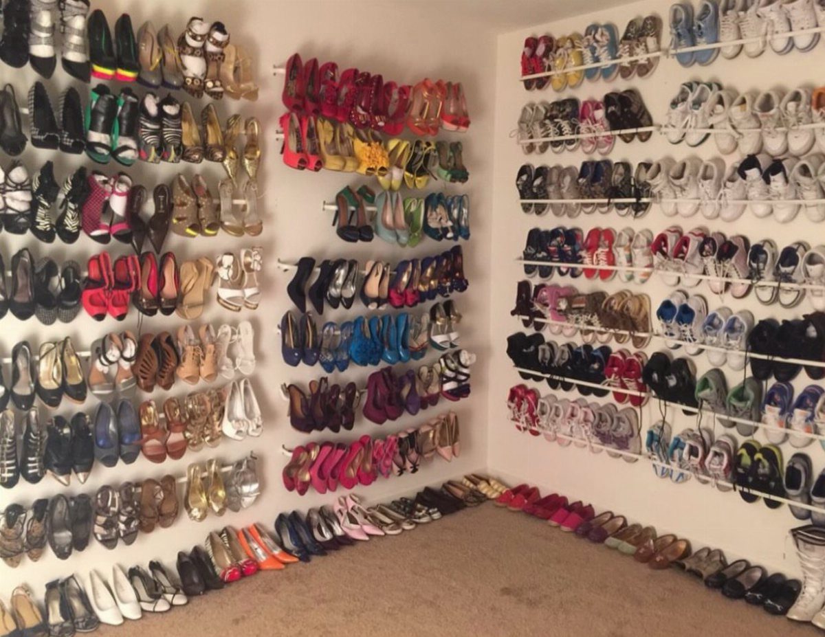 Many colorful shoes organized on white wall-mounted racks in a walk-in closet.