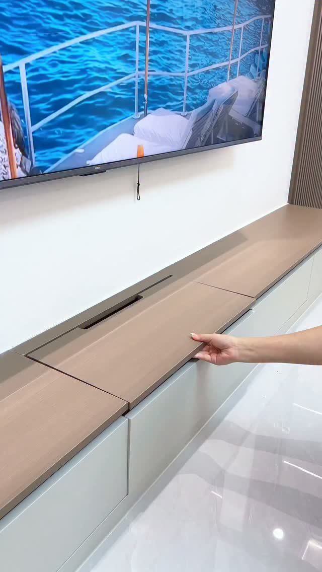 Floating white and wood credenza with a hand opening a concealed storage panel.