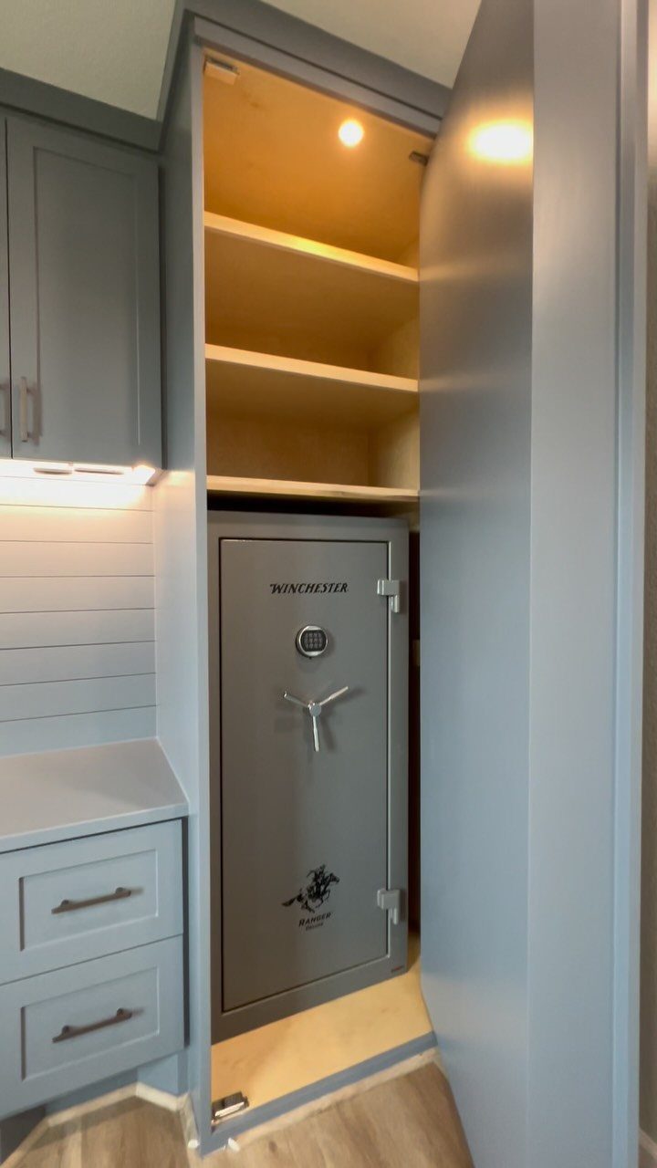 Grey built-in cabinet with an open door revealing shelves and a metal safe.