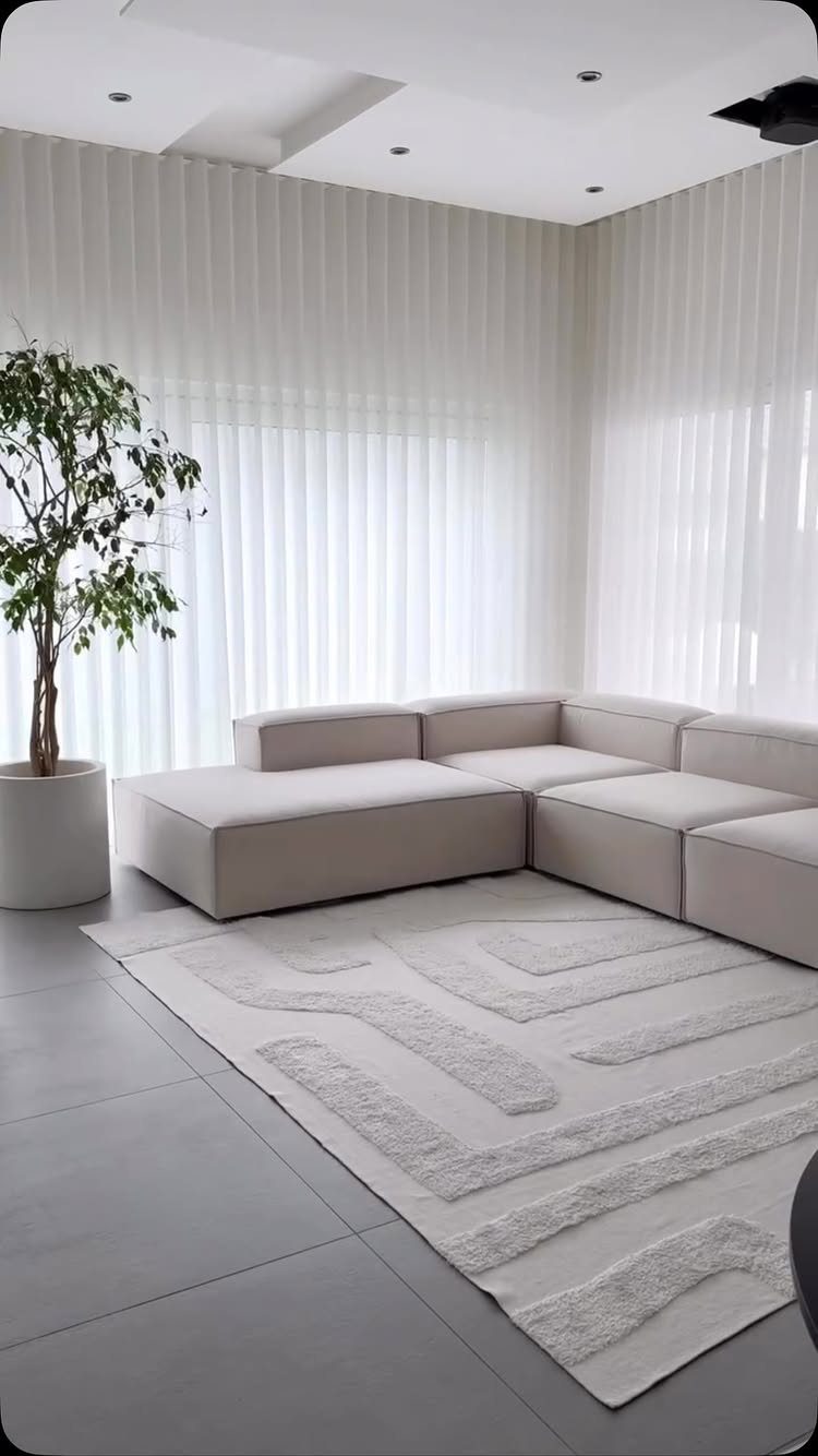 Beige L-shaped sectional sofa with a chaise lounge on a white textured rug.