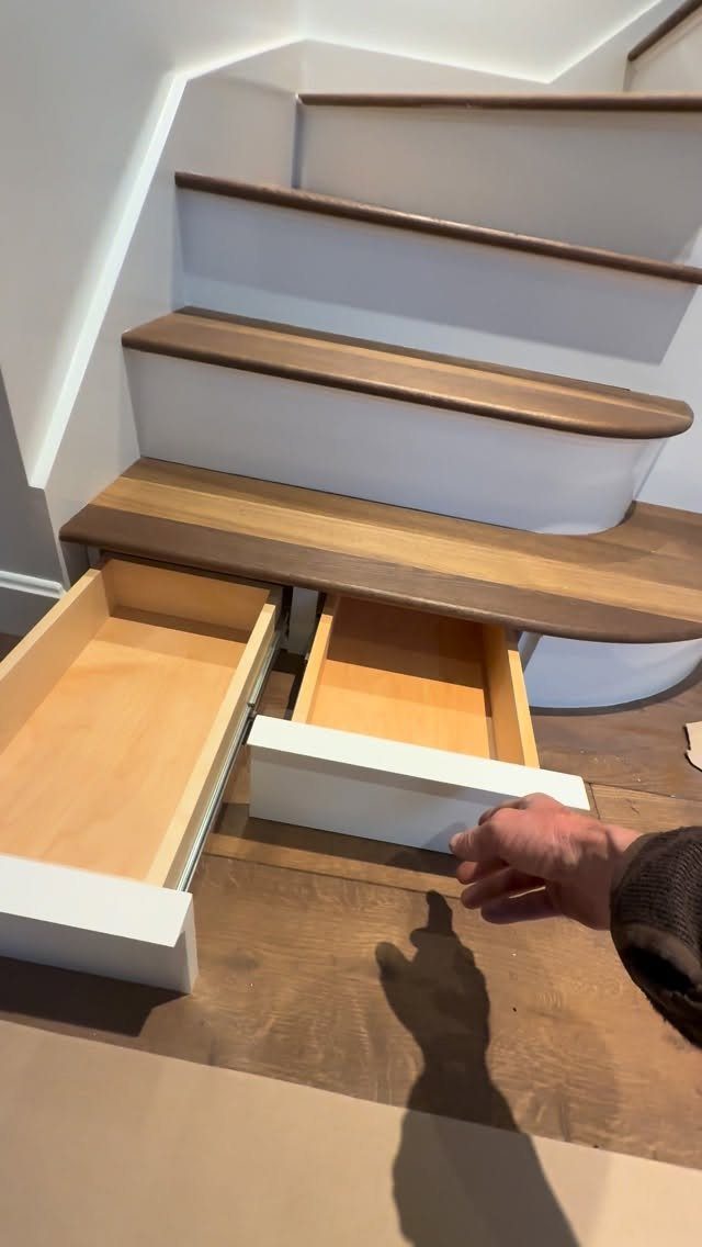 Curved white staircase with built-in wooden drawers extending from the bottom step.