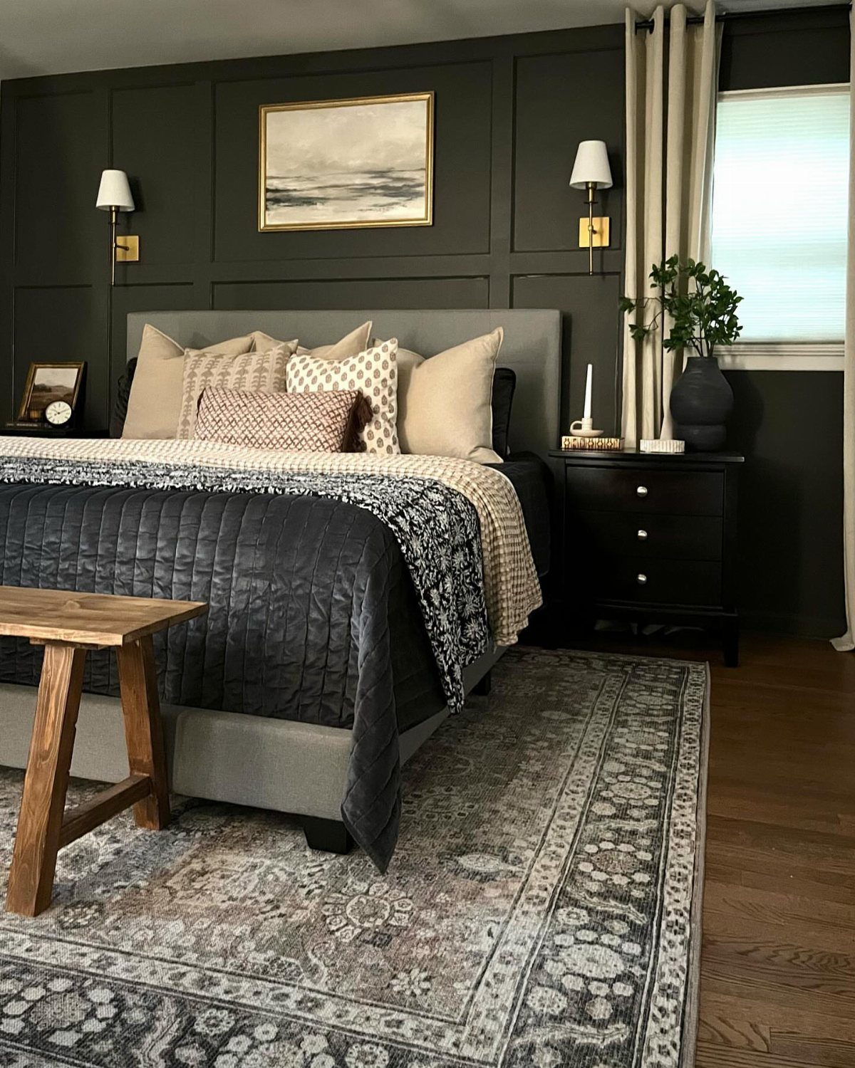 Patterned grey and beige area rug under a bed in a moody bedroom