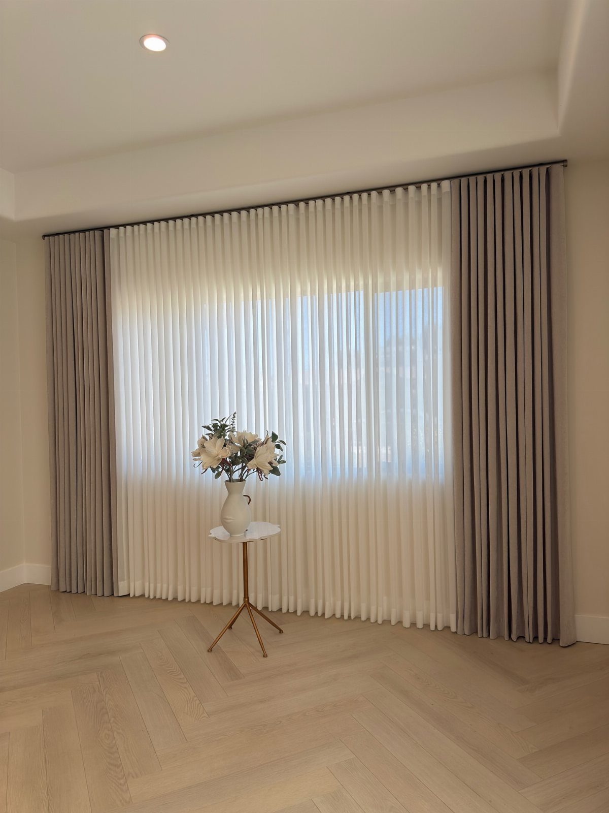 Double curtains with white sheers and grey panels in a modern living room.