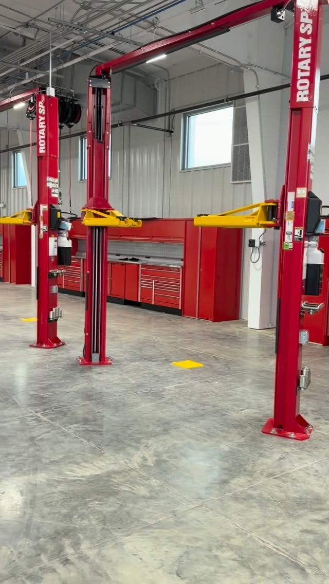 Red hydraulic car lifts and tool cabinets in a clean, professional garage workshop.