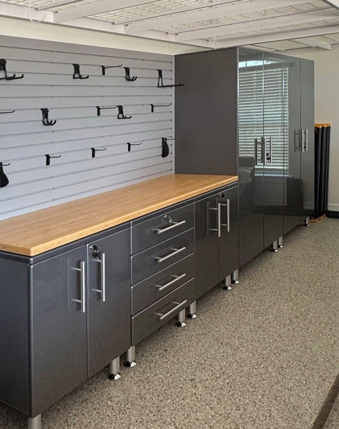 Grey custom cabinets with a light wood countertop in a modern garage workshop.
