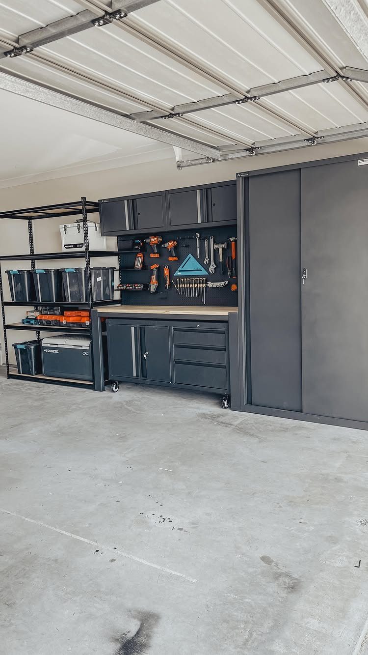 Grey garage workshop with a workbench, tool storage cabinets, and metal shelving units.