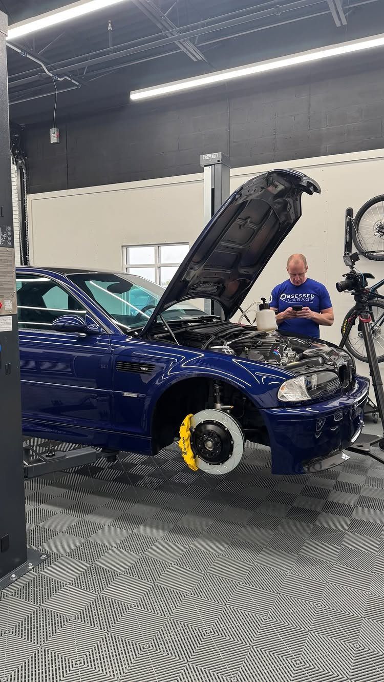 Blue car on a lift in a clean, modern garage workshop with a mechanic.